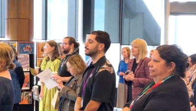 Bunin and other attendees standing whilst listening to NAIDOC Week 2025 guest speakers