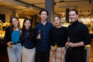 Five attendees standing together smiling at camera at Design for a Difference Event 2025