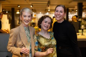 Three attendees standing together smiling at camera at Design for a Difference Event 2025