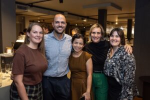 Five attendees standing together smiling at camera at Design for a Difference Event 2025